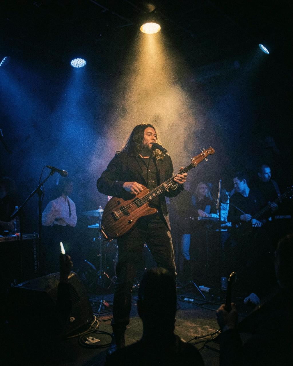 Live bouzouki musician performing on a smoky stage under a gold spotlight